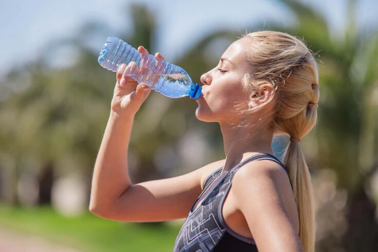 A woman enjoying a glass of water, highlighting the benefits of hydration for health.