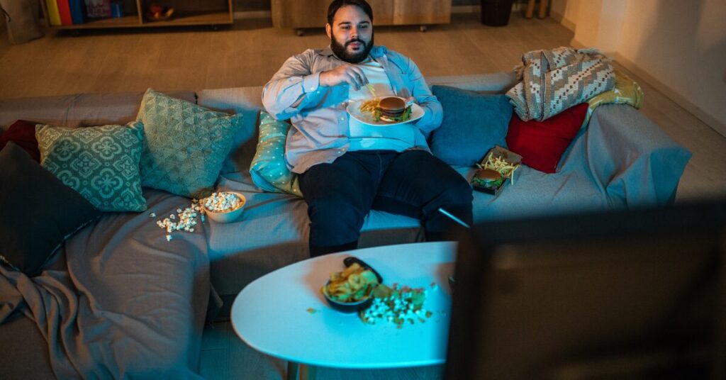 an image of a man eating in front of the TV for an article on how to break bad habits