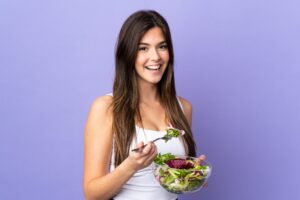 Woman eating bowl of salad